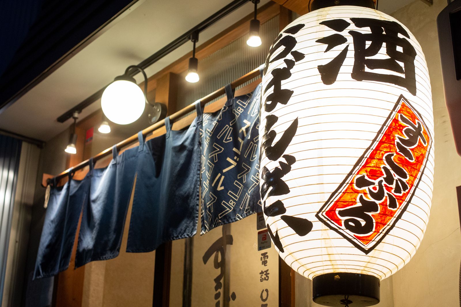 いざかやすこぶるの暖簾と提灯。「酒」「おばんざい」の文字