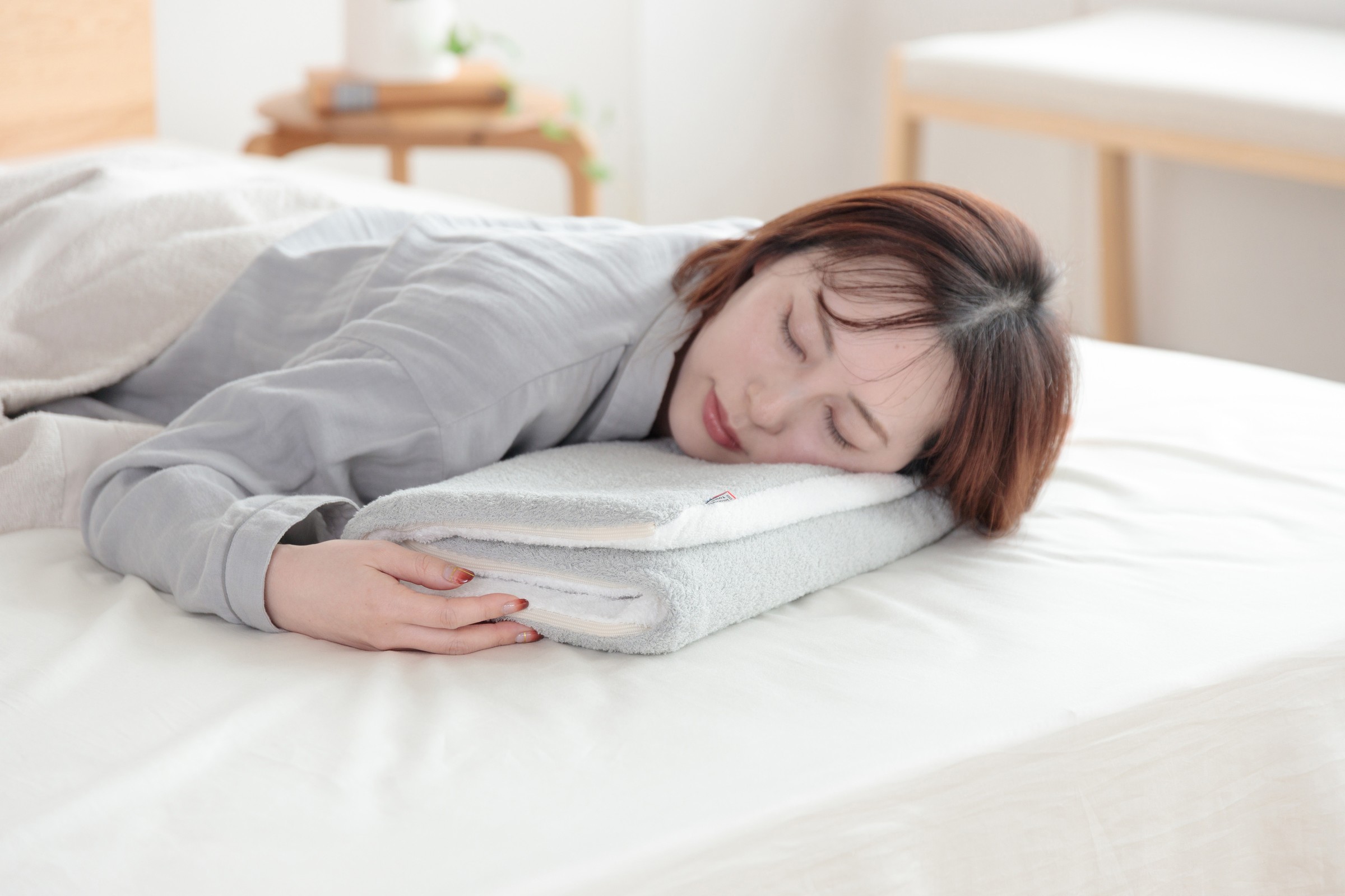 今治タオル枕を折り重ねて横向きに眠る女性