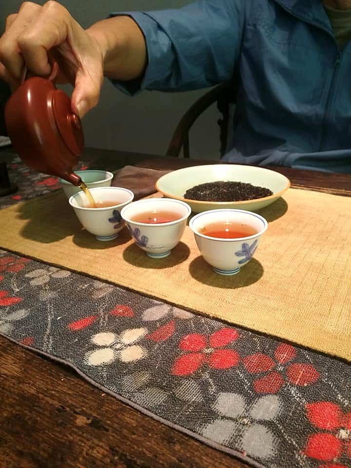 朱泥の急須から、三つの茶杯にお茶を注ぐ
