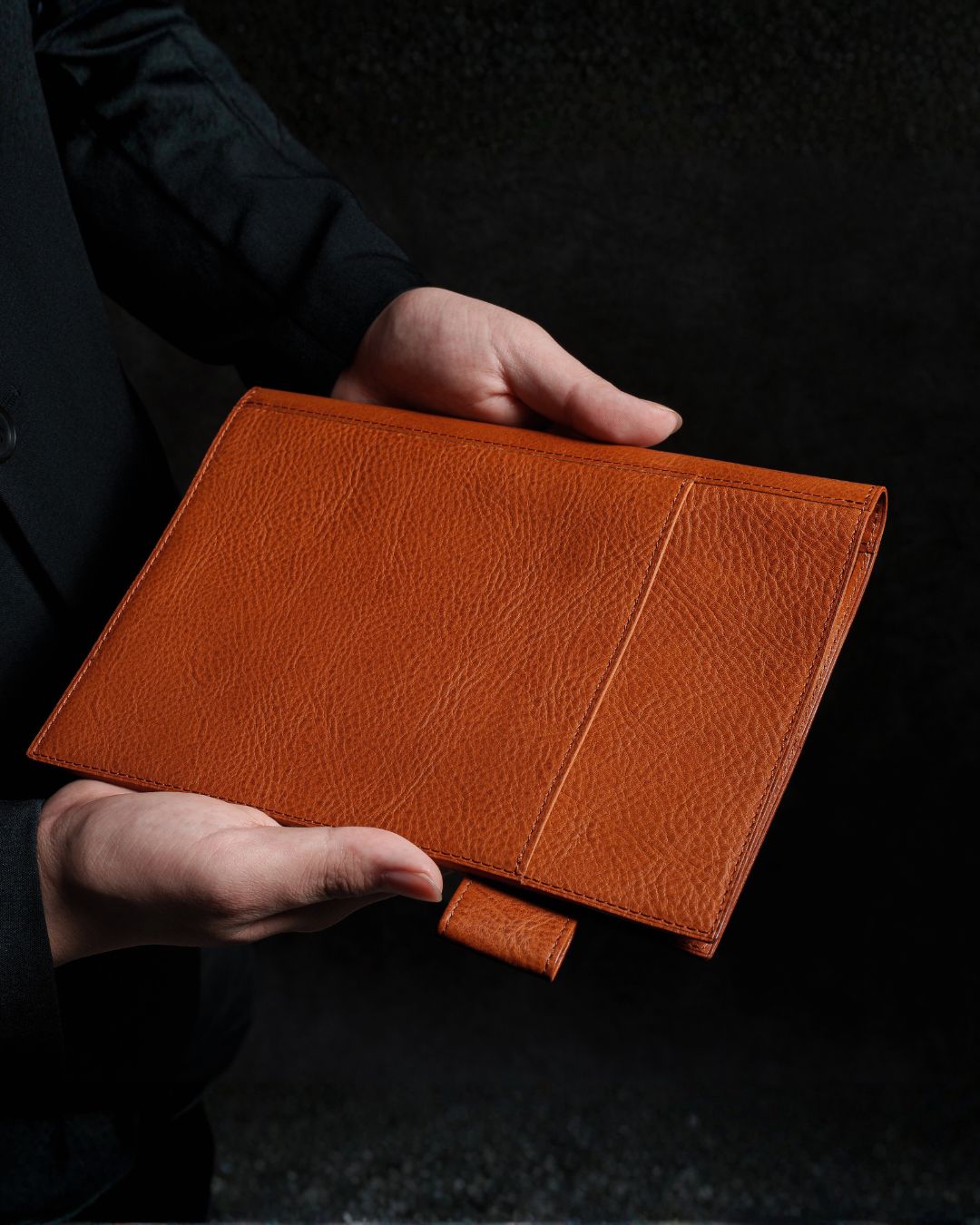 手に持ったコニャック色のflip flap本革ノートカバー
